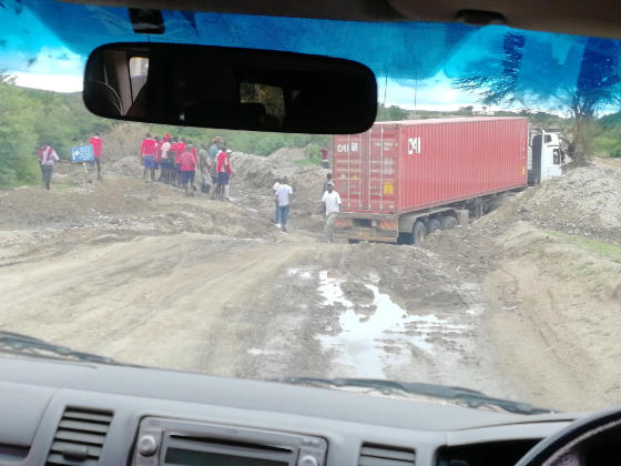 Container lorry stuck in a dip in a mud road